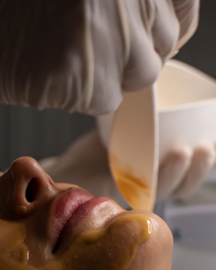 An esthetician applying a warm facial treatment