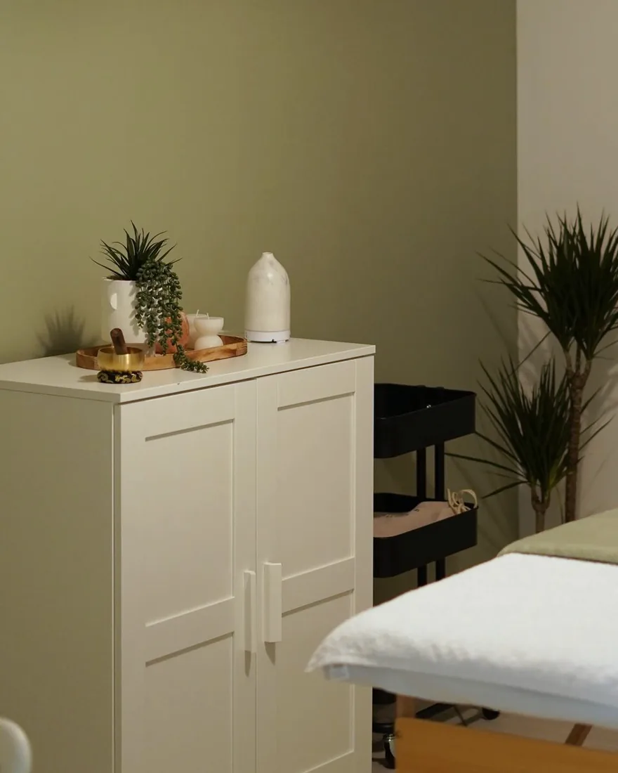 A quiet treatment room with a massage table, plants and soft lighting